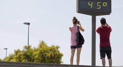 Unos jóvenes hacen una fotografía a un termómetro que marca 45 centígrados en Sevilla el pasado día 18.
 