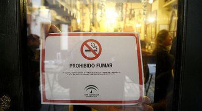 Un bar cuelga el cartel de prohibido fumar ayer, en el centro de Sevilla.