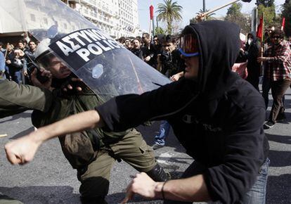Un participante en las manifestaciones en Grecia contra el plan de austeridad convocadas dentro de la huelga general se enfrenta a un policía antidisturbios.