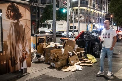 Un hombre pasa delante de varias cajas de cartón junto a los contenedores en la Gran Vía de Madrid, este sábado.