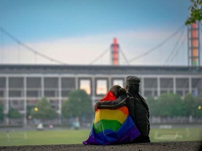 Una pareja con una bandera arcoíris frente al estadio Rheinenergie en Colonia, iluminada en apoyo a la comunidad LGTBI antes de un partido entre Alemania y Hungría, el 23 de junio de 2021.