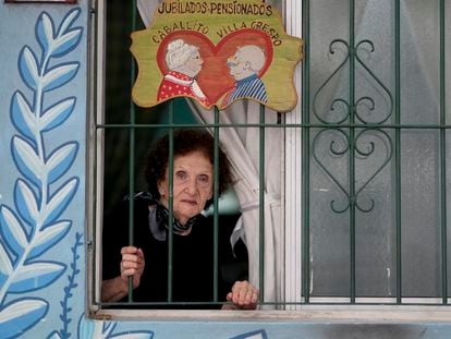 Paulina Najnudel, de 85 años, se asoma por una ventana del centro de recreación para la vejez en Buenos Aires, Argentina, el 12 de abril 2023.