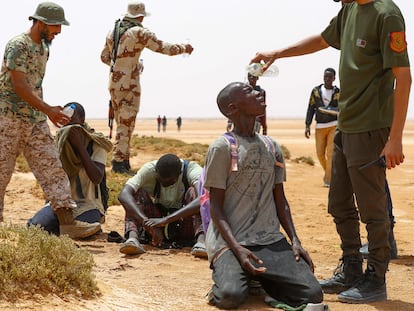 Unos guardias fronterizos libios dan agua a unos migrantes que las autoridades de Túnez dejaron en un área deshabitada de la frontera entre ambos países, el pasado julio.