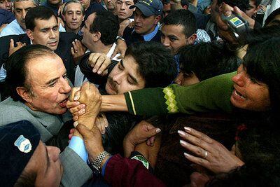 El candidato presidencial Carlos Menem besa la mano de uno de sus seguidores en mayo de 2003.