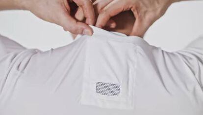 Un hombre coloca el aire acondicionado portátil en el bolsillo habilitado en la camiseta.
