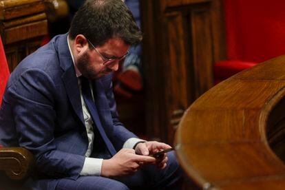 El president de la Generalitat, Pere Aragonés, consulta su teléfono móvil durante una sesión del pleno del Parlament.