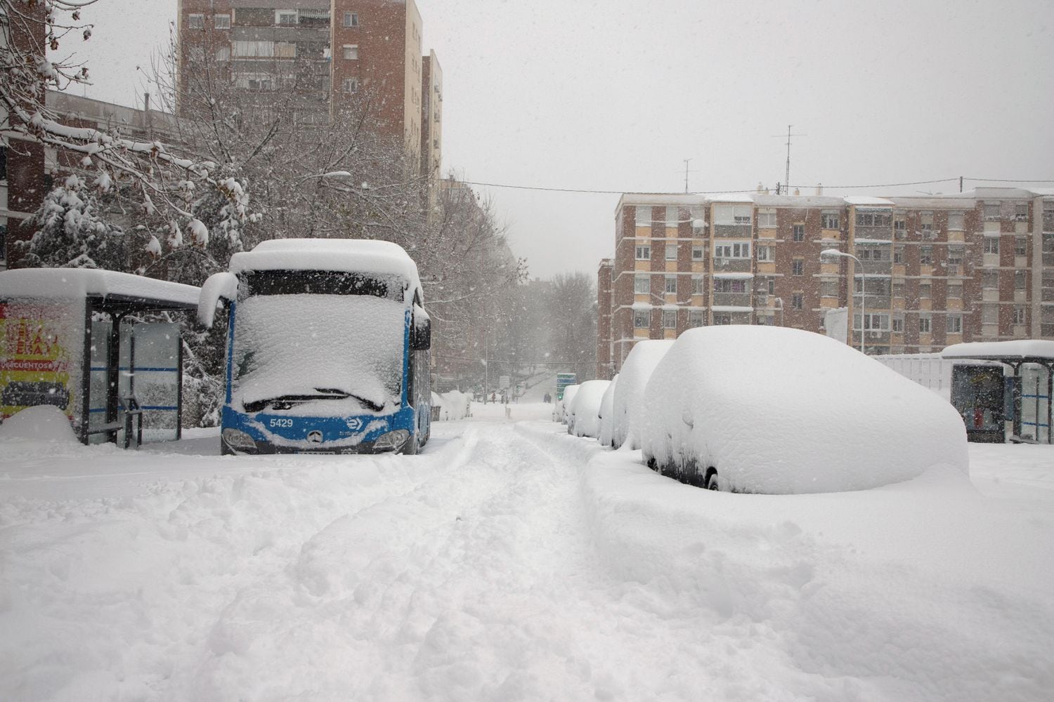 Un autobús de línea de la capital, cubierto por la nieve y abandonado, el sábado en una calle del barrio de La Elipa.