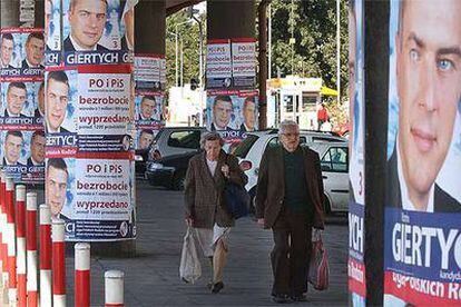 Dos transeúntes circulan por una calle de Varsovia empapelada con propaganda electoral.