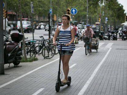 Una mujer circula con un patinete electrico por Barcelona.