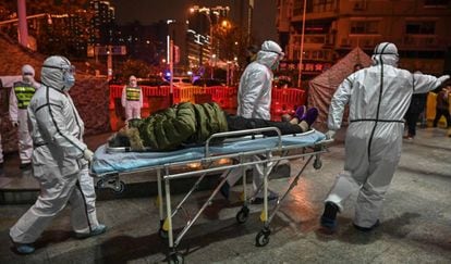 Miembros de los equipos sanitarios trasladan a un enfermo en Wuhan.