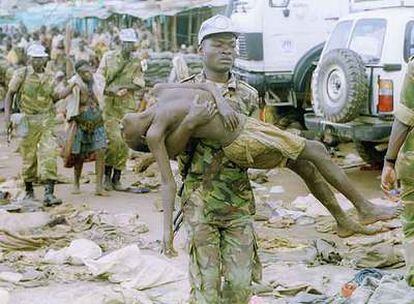 Un <i>casco azul</i> de la ONU lleva en brazos a un refugiado asesinado por el Ejército ruandés.