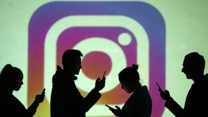 Usuarios de móviles, frente al logotipo de Instagram.