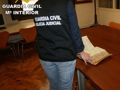 Una agente de la Guardia Civil muestra el libro sustraído y recuperado por el Archivo Histórico Diocesano de Teruel.