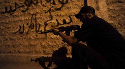 Un rebelde sirio apunta con su arma en una calle de Alepo, este lunes. 