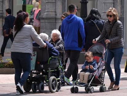 Una mujer empuja un carrito de bebé, mientras otras dos llevan a personas mayores en sillas de ruedas, en una imagen de 2019 en Oviedo.