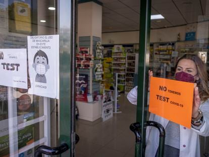 Una farmacéutica coloca un cartel de no disponibilidad de test de antígenos este sábado en Sevilla.