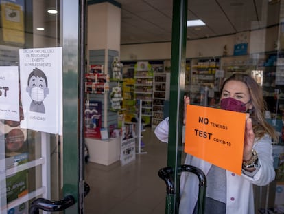 Una farmacéutica coloca un cartel de no disponibilidad de test de antígenos este sábado en Sevilla.