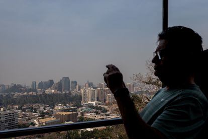 Un turista en el funicular del Parque Metropolitano De Santiago, toma fotografías de la ciudad, mientras la capital se llena de humo debido a los incendios forestales.