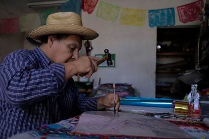 Maestro artesano, Pedro Ortega Lozano utiliza un martillo y cincel para crear papel picado en la víspera del Día de los Muertos en México.