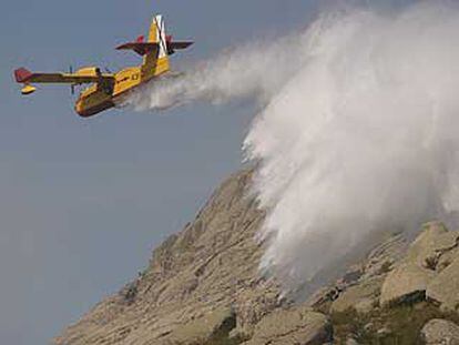 Un hidroavión expulsa agua para sofocar el incendio declarado en el término municipal de Bustarviejo.