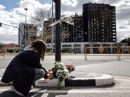Una mujer deja un peluche, este sábado, junto a varios ramos de flores en recuerdo a las víctimas del incendio de un edificio en el barrio de Campanar de València que se ha cobrado la vida de al menos 10 personas.