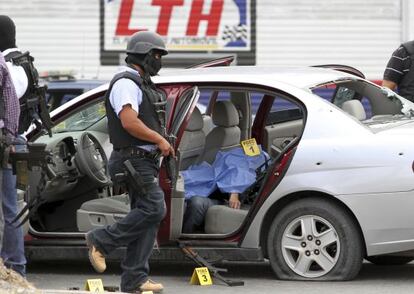 Un policía camina junto a un coche donde yace una víctima de un tiroteo en Saltillo, Coahuila (norte de México).