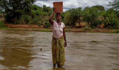 Una mujer de la aldea de Mabilioni posa con un cubo de agua sobre la cabeza.