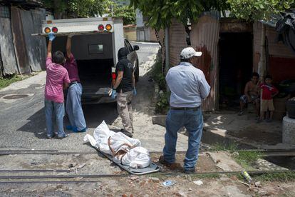 Familiares y miembros del equipo forense de medicina legal de San Salvador trasladan el cuerpo de un joven recientemente asesinado por las pandillas.