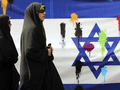 Un par de mujeres iraníes pasan delante de una bandera israelí durante una manifestación convocada para celebrar, hoy, el Día de Jerusalén.