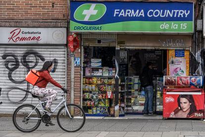 Una repartidora en bicicleta pasa frente a una farmacia en Bogotá (Colombia) en 2020.