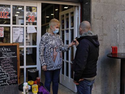 Una empleada de un bar de Sant Just Desvern (Barcelona) comprueba el certificado covid de un cliente en la entrada del local.