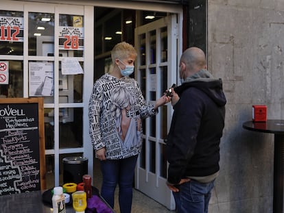 Una empleada de un bar de Sant Just Desvern (Barcelona) comprueba el certificado covid de un cliente en la entrada del local.