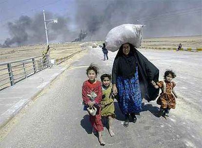 Una mujer iraquí huye de la guerra con sus hijos de la mano y sus pertenencias sobre la cabeza. La foto fue tomada al poco de iniciarse la invasión a las afueras de Basora.
