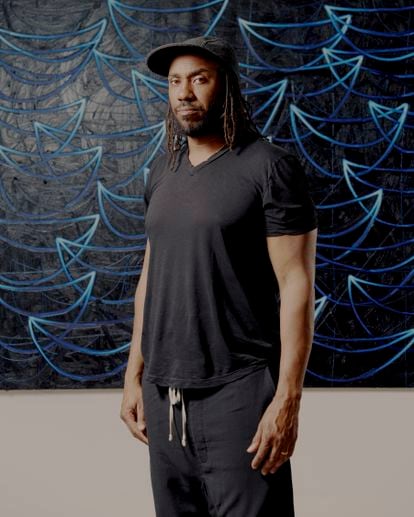 El artista Rashid Johnson en su estudio en Brooklyn, Nueva York, con una obra de la serie 'Seascapes' al fondo. 