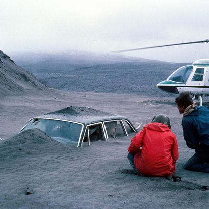Scientists from the United States Geological Survey observe a car half buried by the volcanic ash ejected after the eruption of Mount St. Helens, in the northwestern United States, in 1980.