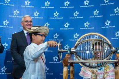 Un niño gira la manivela del bombo en el sorteo del primer barco que atravesará en Canal de Panamá