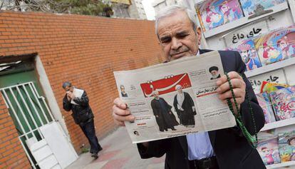 Un hombre sostiene un periódico, este domingo en Teherán, con las imágenes de Rafsanjani y Rohaní.