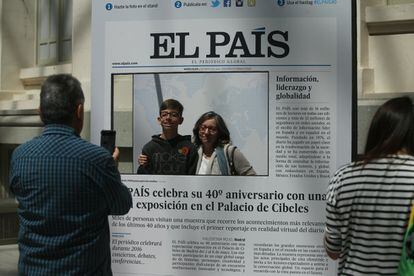 Unos visitantes se fotografían en una portada de EL País.