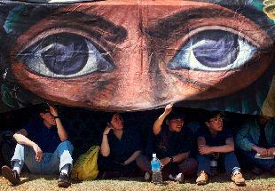 Seguidores de Marcos se protegían del calor en México ayer bajo una pancarta del líder zapatista.