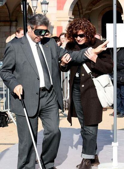 El presidente del Parlament, Ernest Benach, camina con los ojos tapados y un bastón en un acto promovido por la ONCE.