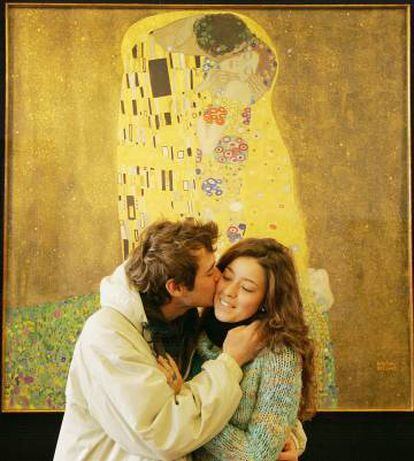 Una pareja se besa emulando el cuadro 'El beso', de Gustav Klimt, expuesto a sus espaldas en Viena.