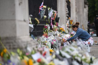 Una mujer deja flores en las verjas del Palacio de Buckingham un día después de la muerte de Isabel II, este viernes, en Londres.