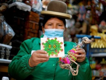 Victoria Acarapi sostiene una figura del coronavirus y un feto de llama como parte de una ofrenda en el mes de la Pachamama en un mercado de La Paz, Bolvia en 2020.