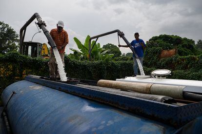 Dos trabajadores llenan camiones cisterna de servicio de agua privado en Caracas (Venezuela).