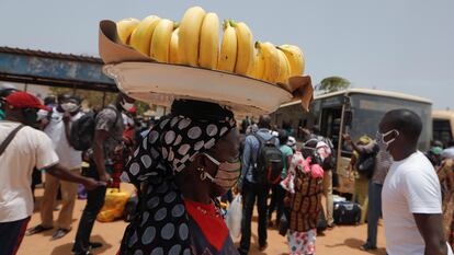 Una vendedora callejera carga con una cesta de plátanos sobre su cabeza por una concurrida calle de Dakar, capital senegalesa, en mayo de 2020.