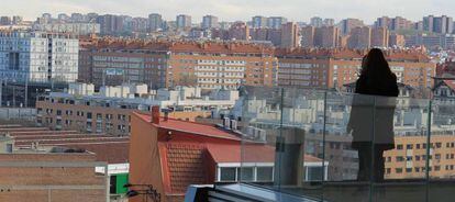 Las viviendas pueblan el horizonte de fondo mientras la silueta de una mujer se dibuja en un balcón.