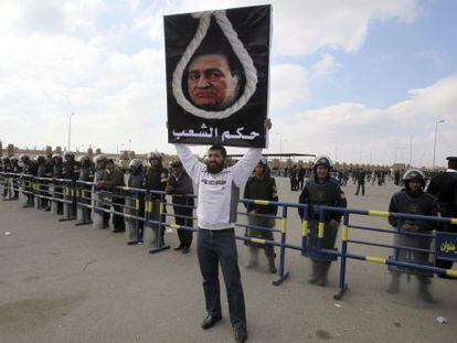 Un detractor del expresidente egipcio Hosni Mubarak, sostiene una pancarta donde se puede leer &#039;veredicto del pueblo&#039;, frente a la Academia Policial donde hoy, se ha reanudado el juicio en El Cairo (Egipto)