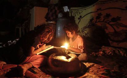 Dos niños palestinos hacen los deberes durante un apagón en Gaza.