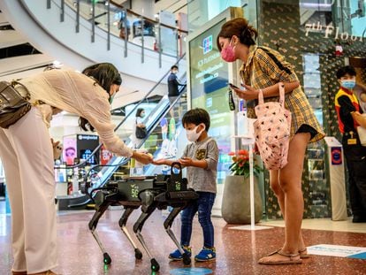 Un robot distribuye desinfectante a los clientes de un centro comercial en Bangkok.