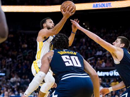Stephen Curry, de los Golden State Warriors, trata de encestar frente a Nikola Jokic, de los Denver Nuggets, la semana pasada en un partido de pretemporada.